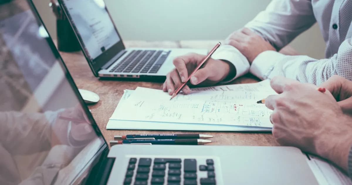 Empresario revisando documentos financieros con calculadora sobre un escritorio